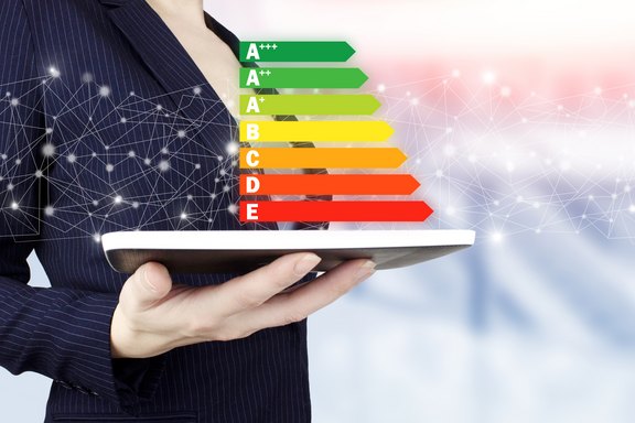 Ein in der Hand gehaltenes weißes Tablet und darüber eine Grafik, die Energieeffizienz symbolisiert.