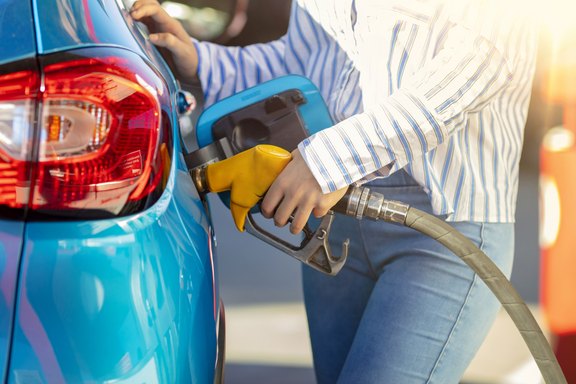 Tanken von Gas an der Zapfsäule. Frau tankt das Auto. Frau an der Tankstelle. Frau füllt ihr Auto mit Benzin an der Tankstelle. Kraftstoff in den Tank pumpen. Detail der Frau, die Auto füllt